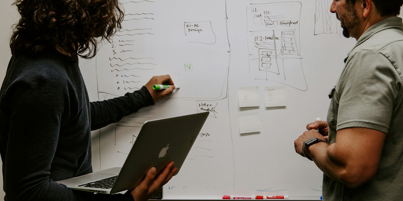 Two colleagues mapping out a plan on a whiteboard