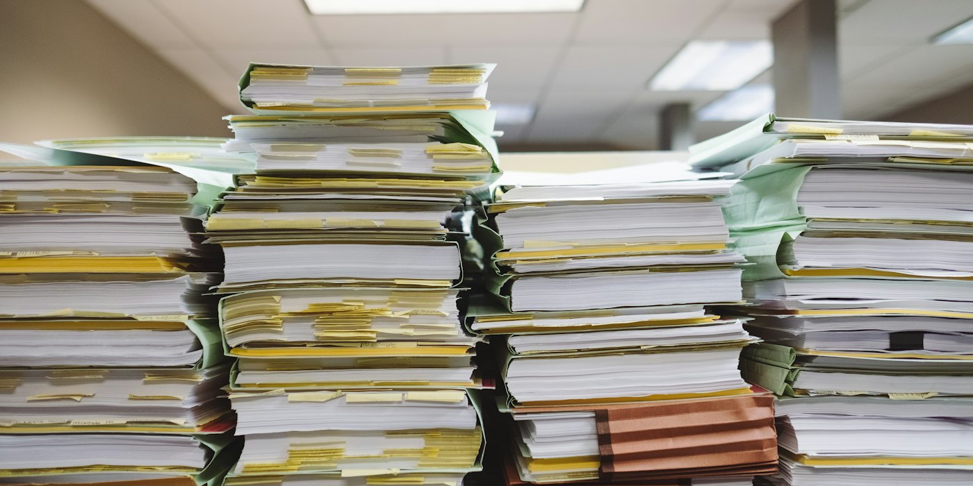 Stacks of paper files and folders waiting to be processed