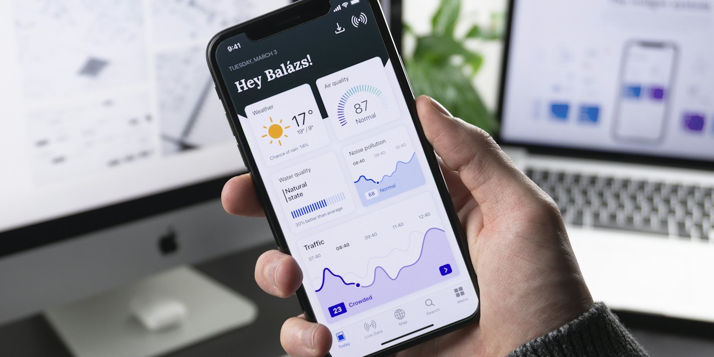 A phone showing a mobile app, with design screens behind it